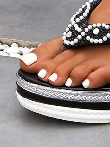 Detail van damesplatformslippers met versieringen van parels en strasssteentjes.