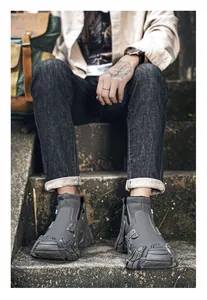 Detail of grey waterproof high-top work boots with side zipper on grey stone steps