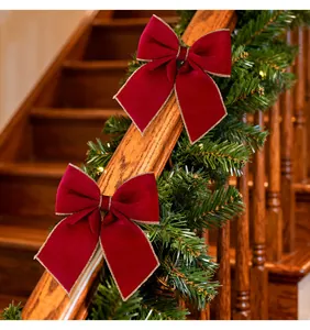 Close-up of red velvet bows with elegant gold trim on a festive staircase garland decoration.