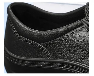 Detail van zwarte antislip chef-schoen met leerachtige textuur en stiksels getoond.