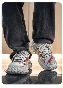 Detailopname van trendy herensneakers met een grove bandenzool en rode accenten.