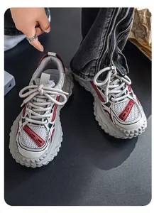 Detail van grove herensneakers met dikke profielzolen en opvallende rode accenten