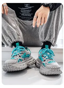 Gedetailleerde weergave van grove herensneakers met grijs mesh en blauwgroene panelen.
