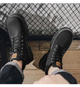 Close-up detail of men's black lace-up outdoor Martin boots on a wooden floor.