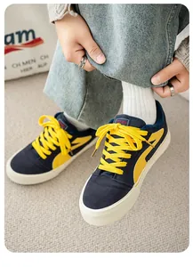 Detailopname van marineblauwe canvas sneakers met fleecevoering en gele veters.
