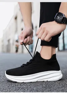 Close-up van iemand die veters strikt van zwarte gebreide sneakers met dikke witte zolen