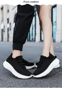 Detailopname van zwarte ademende mesh sneakers met dikke witte golvende zolen voor heren.