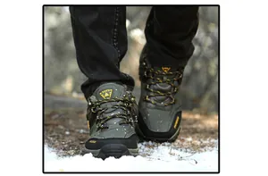 Close-up detail of durable waterproof men's winter hiking shoes walking on snowy ground
