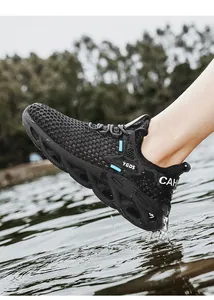 Close-up of breathable black mesh running shoe stepping into splashing water