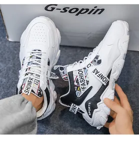 Close-up detail of white chunky sneakers for men featuring thick soles and sports patterns
