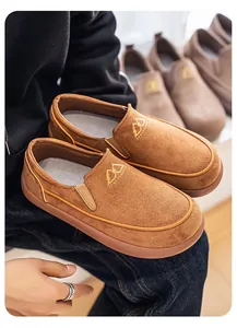 Primer plano de mocasines de ante marrón con un detalle de logotipo de montaña dorado