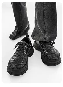 Close-up detail of black platform derby shoes featuring a unique woven texture on the toe