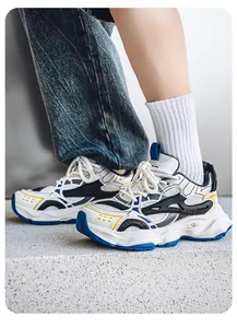 Detailed side view of white and blue retro chunky sneakers for men on a stone step