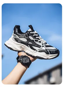 Side view of black and white men's chunky retro sneakers held against a blue sky