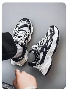 Detailed top-down view of black and white chunky sneakers on a smooth gray surface