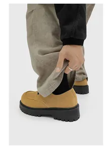 Vista dettagliata delle scarpe derby in camoscio kaki con suola spessa nera e pantaloni a coste