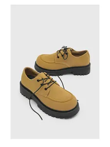 Vista dettagliata delle scarpe Derby in camoscio giallo senape con spessa suola nera.