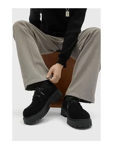 Dettaglio di scarpe Derby nere da uomo con suola spessa abbinate a pantaloni grigi