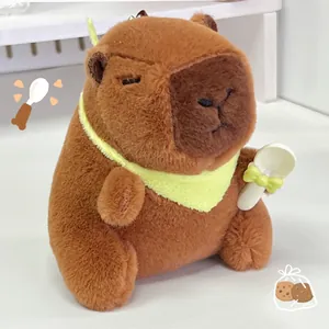 Schattige capibara pluche sleutelhanger met geel slabbetje en een kleine witte lepel.