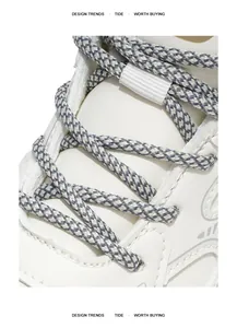 Primer plano de cordones texturizados grises y blancos en zapatillas blancas de estilo dad