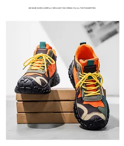 Primer plano de botas de montaña altas en naranja y verde oliva con cordones amarillos.