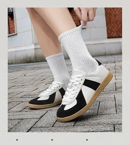 Close-up view of black and white GAT sneakers with classic gum sole shown on pavement