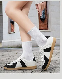 Detailed side view of classic white and black leather German army trainers on feet