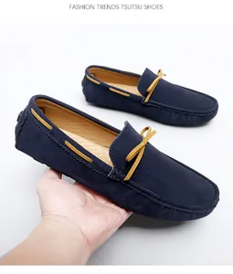 Detailed macro view of navy blue suede loafers with yellow leather bow accent held by hand