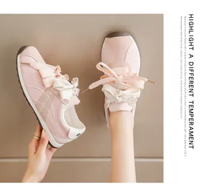Detail view of pink suede sneakers for women, showcasing dual-tone laces and stitching.
