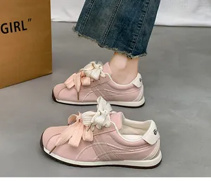 Detailed view of stylish pink suede sneakers featuring decorative oversized bow laces
