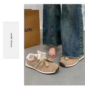 Detailed view of khaki suede sneakers featuring large bow-tie laces and thick rubber soles.