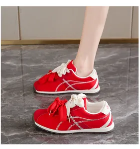 Detailed view of red suede women's sneakers featuring a large ribbon bow and white stripes