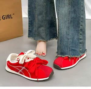 Close-up of red suede women's sneakers with decorative large bow laces and contrast stitching