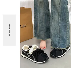 Close-up of black suede sneakers with decorative double bow laces and white stitching