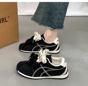 Stylish black suede sneakers featuring white zigzag stitching and thick cream laces.