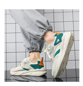 Vista laterale di sneakers basse traspiranti da uomo con dettagli verde e arancio.