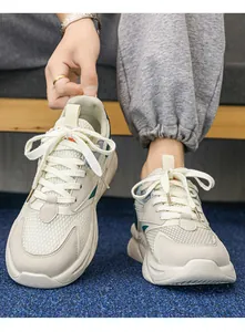 Primo piano di sneaker bianche chunky da uomo traspiranti con accenti verde acqua e suola spessa.