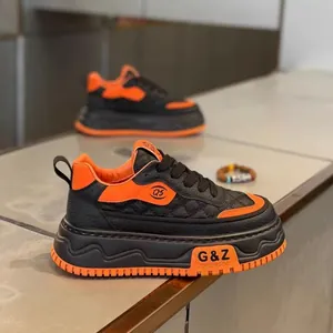 Vista detallada de zapatillas retro con suela gruesa en cuero negro y naranja de diseño.