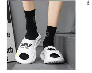 Detaillierte Ansicht der weißen EVA-Slipper mit Smile-Aufdruck auf grauen Betontreppen