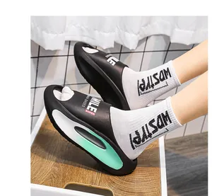 Nahaufnahme von schwarzen EVA-Sport-Slippern mit weißem SMILE-Text und mintgrünen Details
