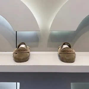 Λεπτομέρεια από χακί σουέτ μοκασίνια με λουράκι λογότυπου MEHECHADXE σε έκθεση