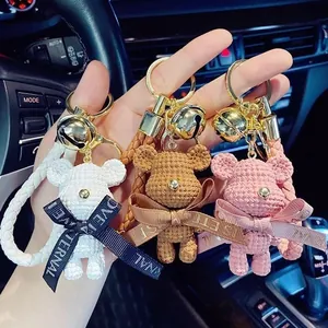 Close-up of knitted bear keychains in white, brown, and pink with bells and ribbons
