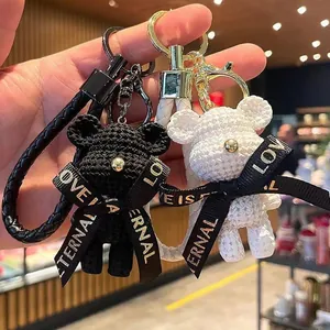 Close-up of black and white woven-texture bear keychains with "Love is Eternal" ribbons.