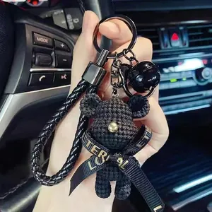 Detailed macro view of black handcrafted crochet bear keychain with ribbon and bell