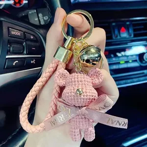 Handmade pink crochet bear keychain featuring golden bell and woven strap décor