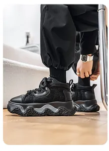 Close-up of black chunky sneakers with textured wave sole on light wooden floor.