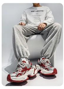 Détail de baskets chunky pour hommes en maille rouge et argent portées par un mannequin de mode.