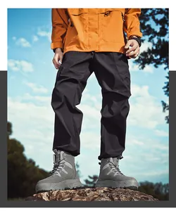Grey waterproof outdoor military boots for men with thick soles on rocky terrain