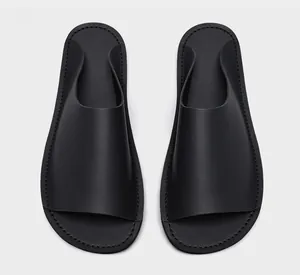 Vue de dessus de claquettes minimalistes en cuir noir pour homme avec coutures fines.