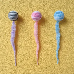 Vista dettagliata di tre palline di peluche colorate per gatti con code pelose vive